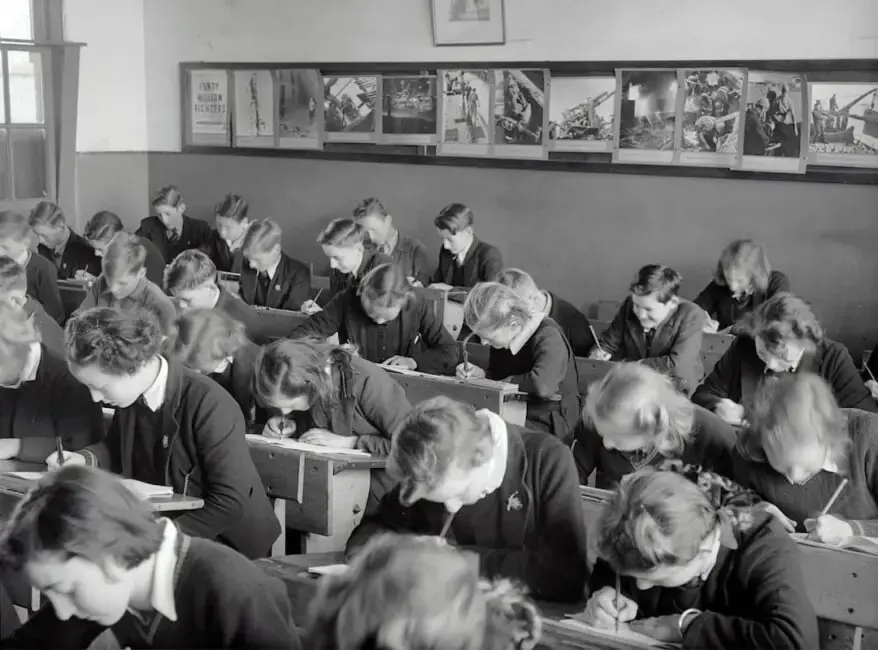 A black and white photo of a classroom with many students sitting at desks.