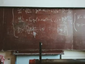 A blackboard in a classroom with writing on it.