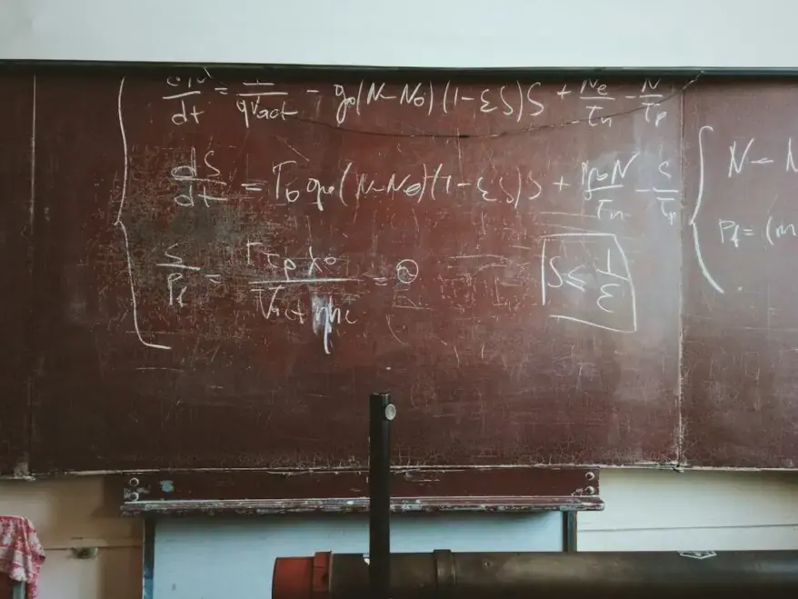 A blackboard in a classroom with writing on it.